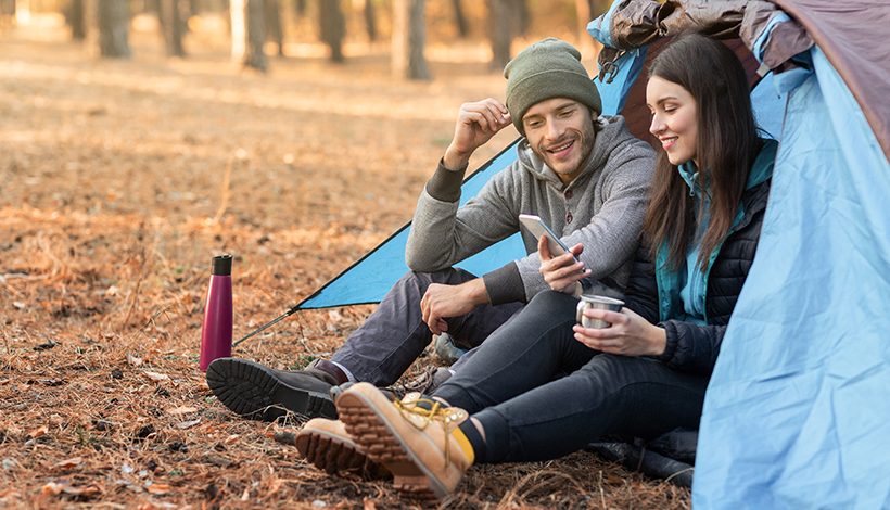 Couple camping looking at phone