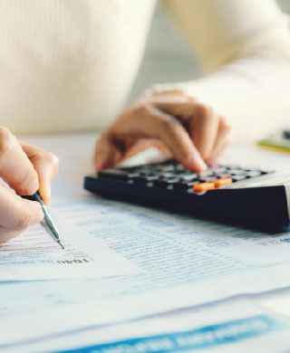 Close up of man typing on calculator and filling out forms.