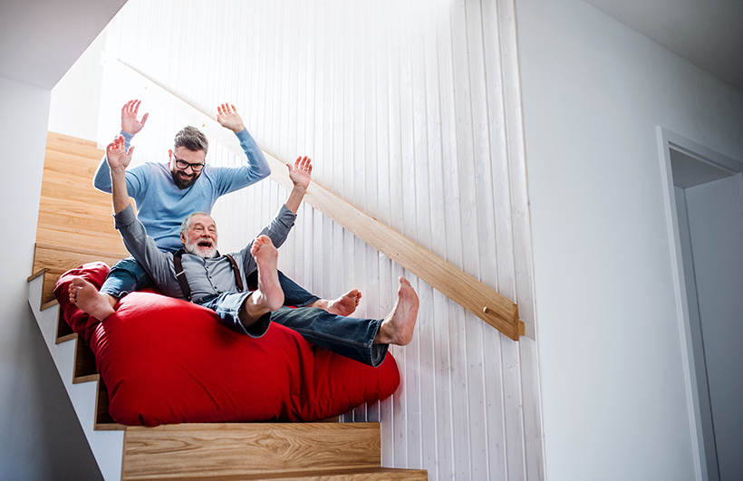 Son with older father sliding down stairs