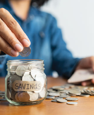 Woman putting coins in savings jar.